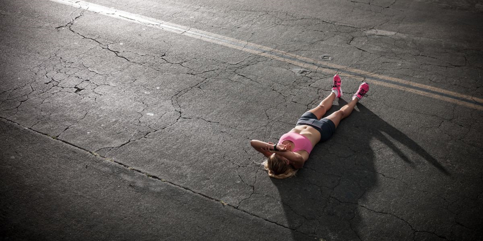 Joggerin liegt erschöpft auf dem Teer